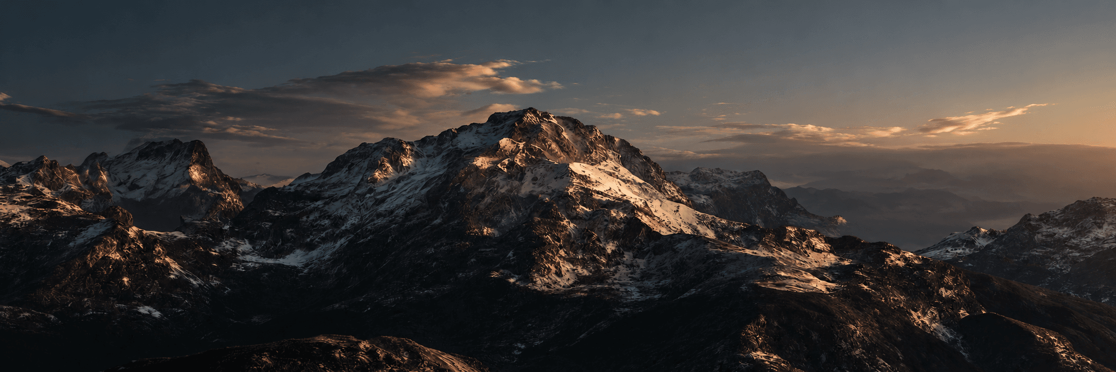 Sunlit snow-capped mountain range at dusk