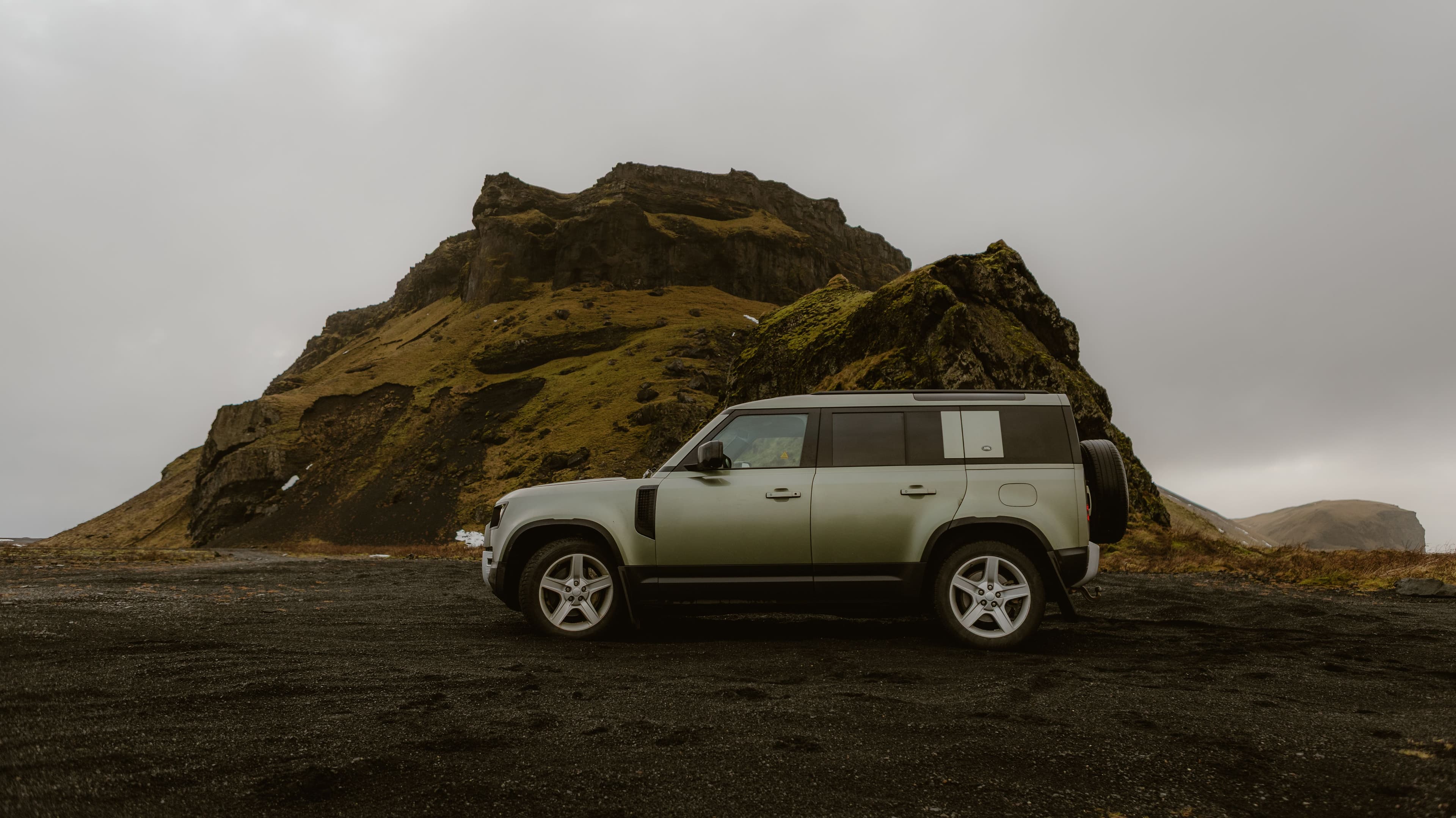 Luxury SUV parked before a dramatic volcanic mountain landscape