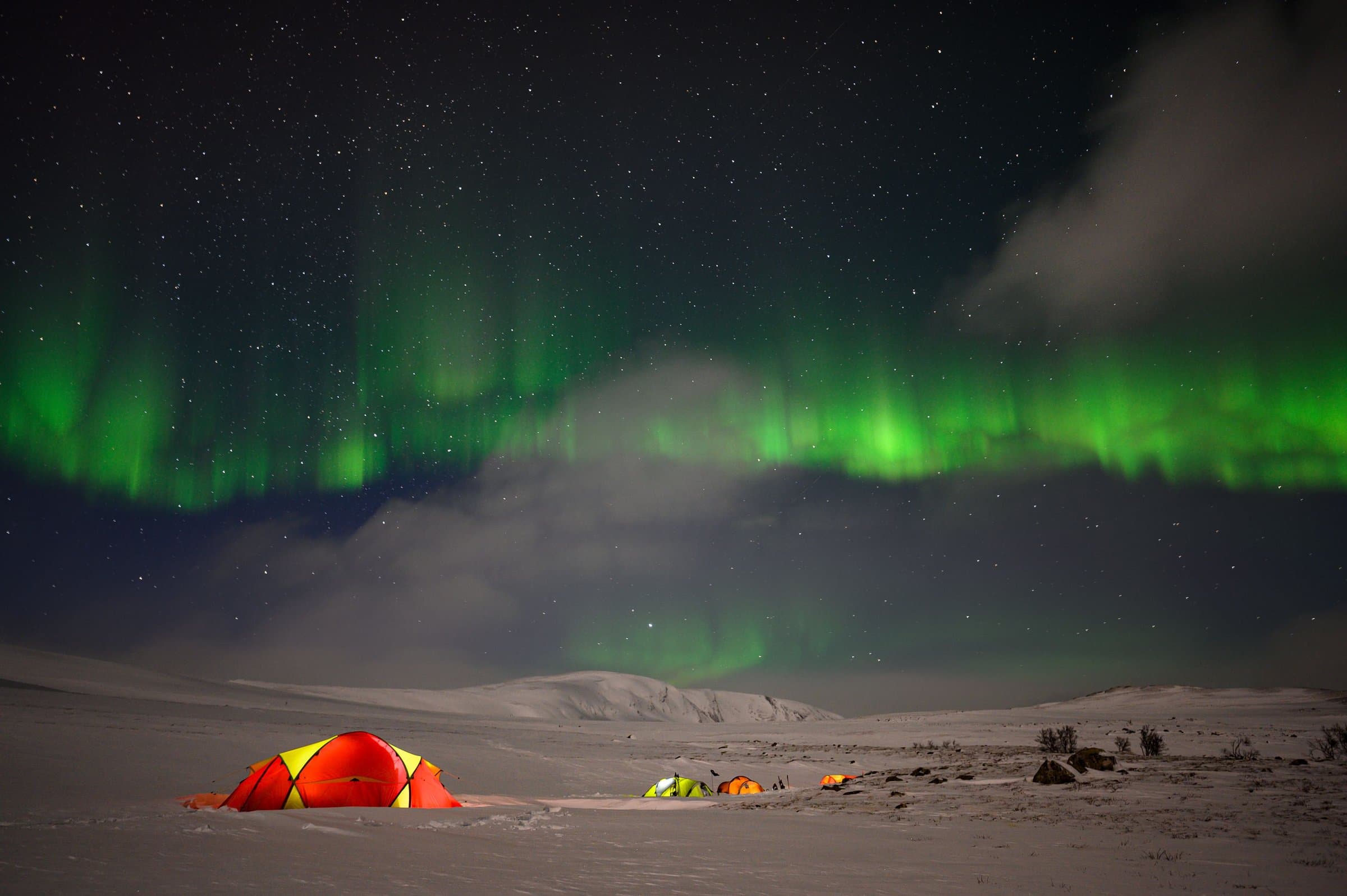Northern lights over a polar camp with glowing tents
