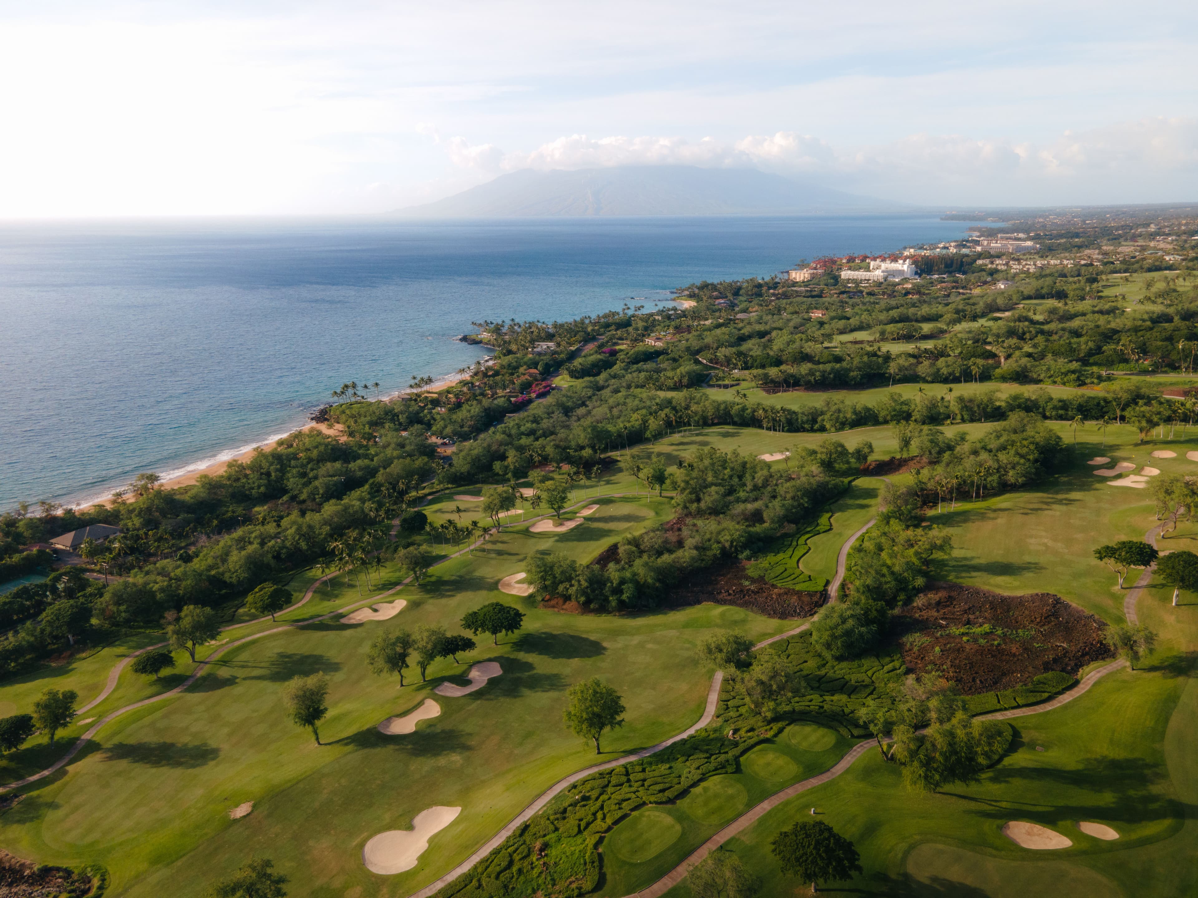 Aerial view of a cinematic coastal golf course fairway beside the ocean