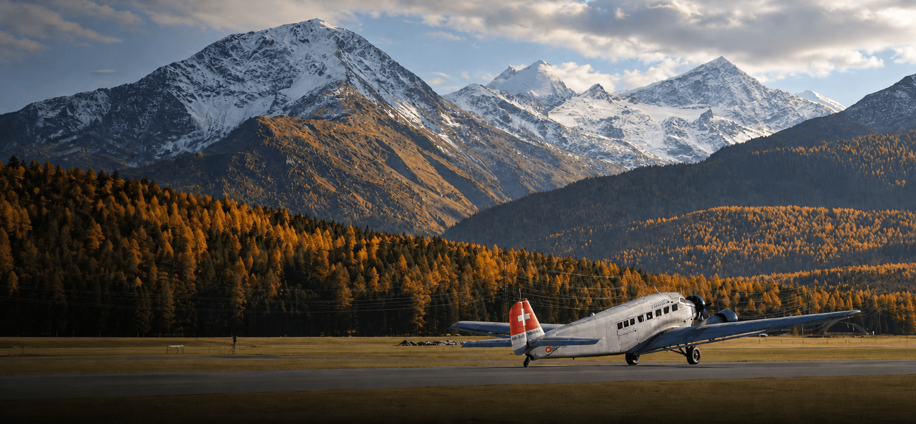 Vintage propeller aircraft on an alpine airfield beneath snow-capped autumn peaks